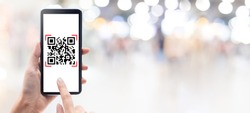 Hand using mobile smart phone scan Qr code on shopping mall banner background. Barcode reader, Qr code payment, Cashless technology, Digital money concept.