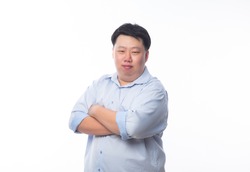 Asian fat man in blue shirt arms crossed and looking to camera isolated on white background.
