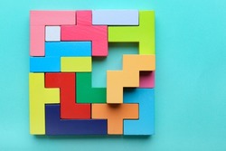 Concept of creative, logical thinking. Different colorful shapes wooden blocks on light background. Geometric shapes in different colors. Child development. Riddle and its solution. Logic tasks.