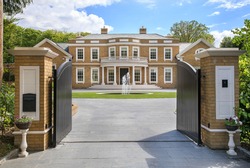 Looking through grand entrance gates to an elegant modern mansion