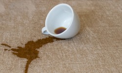 Spilled cup of coffee on the sofa with dirty stain.