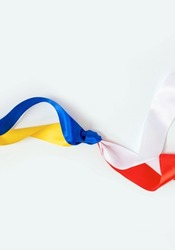 Two flags Poland and Ukraine tied to a knot on the white background. The friendship and donation from Poland to Ukraine during the War