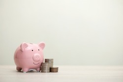 pink piggy bank smiling and coins on the table, for saving money wealth, and financial concepts, copy space