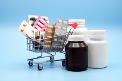 Medicine concept. Various capsules, pack of medicines in shop trolley with medicine bottles on a blue background, Pills concept, Buy and shopping medicine.
