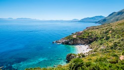 The perfect secret beach: white pebbles beach and turquoise sea, surrounded by luxuriant vegetation of the natural reserve “Riserva dello Zingaro”, San Vito Lo Capo, Sicily, Mediterranean Sea, Italy.