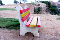 An empty red and yellow stone bench at park in india