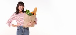 Happy Asian woman holding paper bag full of fresh vegetable groceries isolated on white copy space background.	