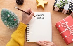Woman hand writing New year's resolution on note paper in new year day.
