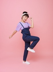 Cheerful Asian child girl celebrate with raised fists looking at camera isolated on pink background.