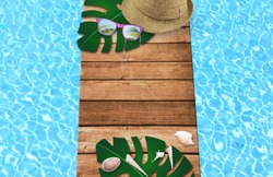 Summer time in vacation holiday, sunglasses, shell with hat on wooden floor and blue swinmming pool in the hotel. Empty space you can place your text or information.