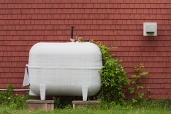 Heating fuel oil tank beside exterior wall.
