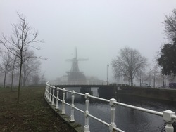 Traditional Dutch windmill and bridge on a foggy day in Haarlem, the Netherlands.
