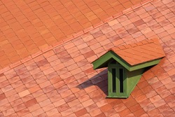 High angle view of green attic window on concrete tile roof in vintage style