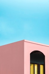Manipulation techniques for colorful architectural background design. Glass window inside of arch wall frame of pink modern house building against blue sky in pastel colors tone style