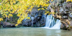 the famous waterfall atysh flowing from a karst funnel in the Ural mountains of Bashkortostan on an autumn sunny day.