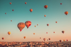 Thousands of colorful hot air balloons flight above mountains - Cappadocia panorama, sunrise view. Goreme valley wide landscape. Vintage retro orange blue toning filter. Tourism, travel, holidays