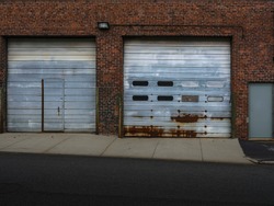 Rusted garage doors in old red brick building on paved street