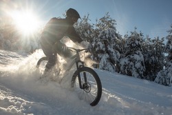 Snowy descent with a mountain bike. Snow downhill with bike, mtb action in winter, with deep snow and sun as a backlight.