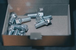 Automotive screws or set of wheel screws lying in a cardboard box. Brand new set of car wheel screws.