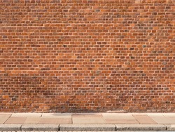 Red brick wall with sidewalk