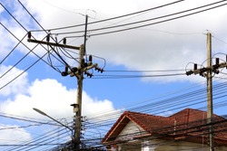 electric pole with blue sky background and Red house roof