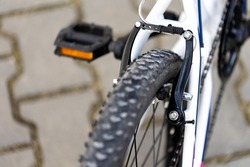 White children's bike, close-up of the V-brake shoes and the tire tread. Blurred background, photo taken in natural, soft light