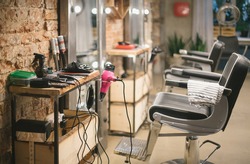 Workshop of hairdressers. Beauty salon with chairs, hair dryers, combs and mirrors