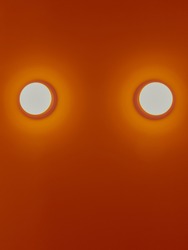 Two white round light bulbs on orange wall. Background and textured concept.