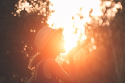 Woman blowing kiss and holding sun in forced perspective.