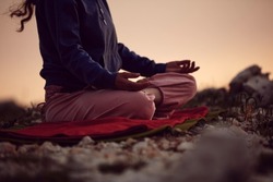 Woman practicing yoga outdoors in sunset sunrise time.