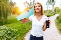 Girl with a skate in the Park, drinking a drink with a glass bottle, summer mood