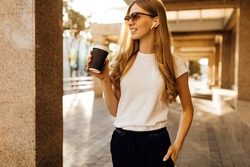 Business young woman in sunglasses walking in city with cell phone