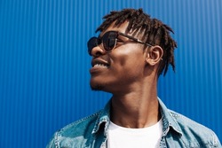 portrait of an african guy in sunglasses, on a blue background, black guy model, looking to the side