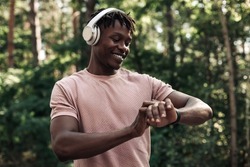 Male runner, American man checking fitness progress on his smartwatch, Black man using fitness app to track workout results while walking in the woods in nature