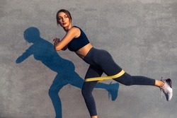 Beautiful sportive woman doing exercises with a resistance band, an athlete with a work band with an elastic band outdoors, Young woman performing fitness exercises on the street