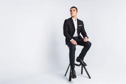 Portrait of the beautiful posing in a Studio. White background, isolated. Stylish business man, Stylish man sitting on a designer chair