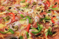 Closeup freshly baked pizza with mozzarella cheese, salami, mushrooms, tomato sauce, olives, green peppers, and onions. Shallow depth of field