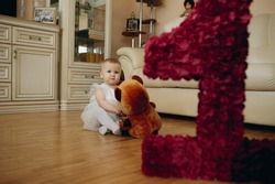 cute little gicute little girl turned 1 year old holding teddy bear toy. Child birthday celebration. Image with selective focus
