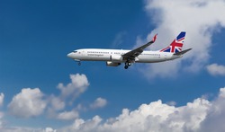 Commercial custom passenger aircraft with British flag on the tail. Blue cloudy sky in the background