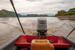 Old outboard motor with its gasoline canister close by in a river in Colombia