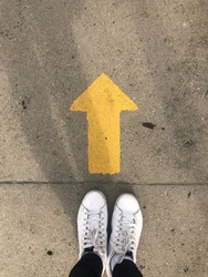 Yellow straight arrow sign and white shoes. Straight direction concept. Journey concept
 