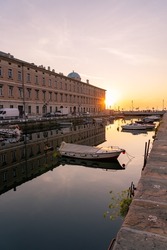 Sunset over Canal Grande di Trieste with beautiful buildings and refletion on the water.