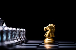 Golden horse chess encounters with silver chess enemy on chess board and black background. Market or business competitor concept.