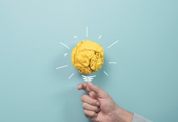 Businessman holding yellow scrap paper ball with illustration painting for virtual lightbulb. It is creative thinking idea and innovation concept.
