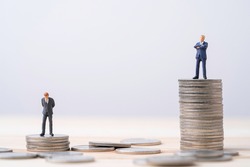 Miniature rich man  and poor man standing standing on different height coins stacking , Inequality income and salary concept.