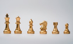 Golden chess include king queen horse ship and pawn on white background.