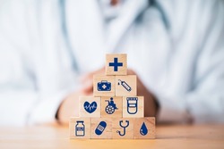 Doctor putting and stacking wooden block cube which print screen health care and medical icons for healthy and wellness concept.