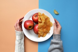 a plate of chips and red apples. A person chooses between healthy and unhealthy food