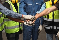 Group of technician engineer or worker in protective uniform with hardhat standing and stacking hands celebrate successful together or completed deal commitment at heavy industry manufacturing factory
