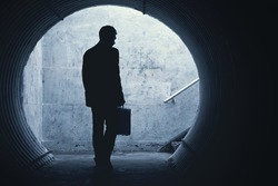 Businessman in Silhouette Walking in a dark tunnel. With room for your Text